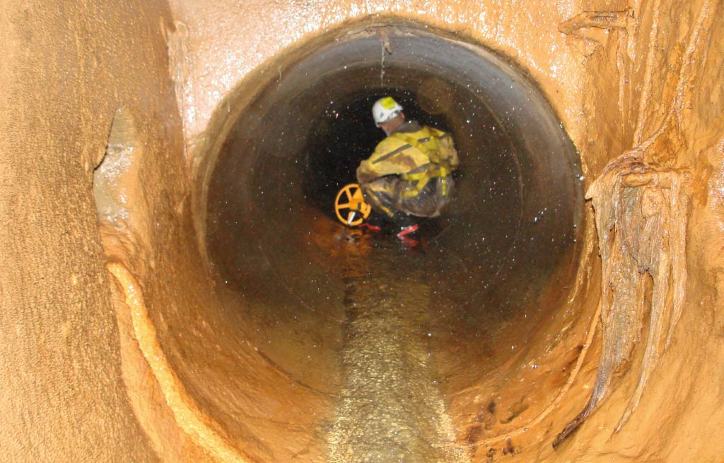 A worker with safety clothing in the confined space of a pipe