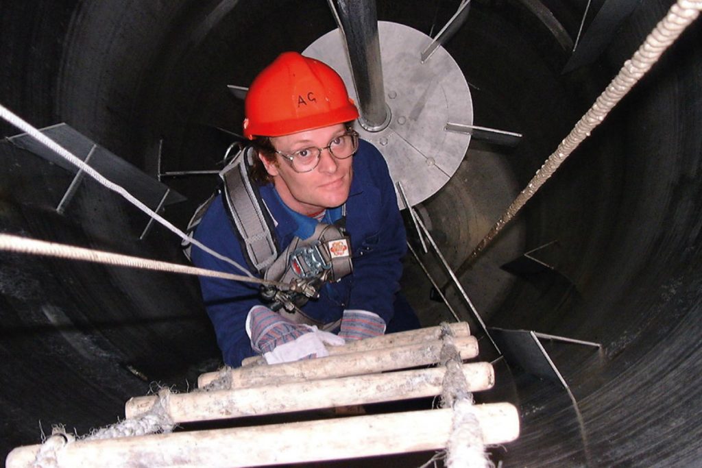 A worker climbing a ladder from a confined space